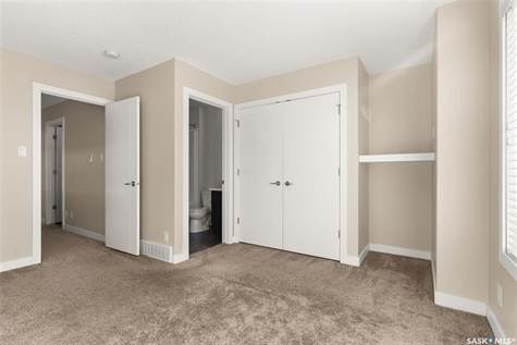 Unfurnished bedroom featuring light carpet, a closet, and ensuite bath