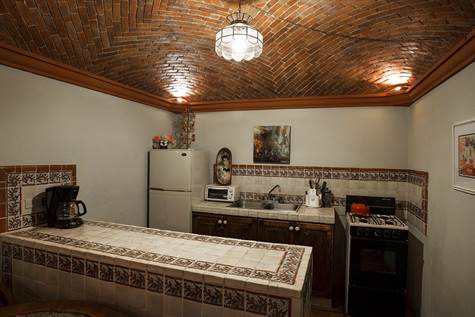 Kitchen of guest casita with boveda ceiling and hand-painted tile