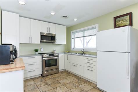 Kitchen has been Updated w/Pot Lights, Ceramic Tile Floors, New Modern White Cupboards, New Countertops, OTR Microwave and Stainless Steel Stove