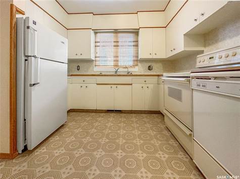 Kitchen with cream cabinetry, tasteful backsplash, sink, light tile floors, and white appliances
